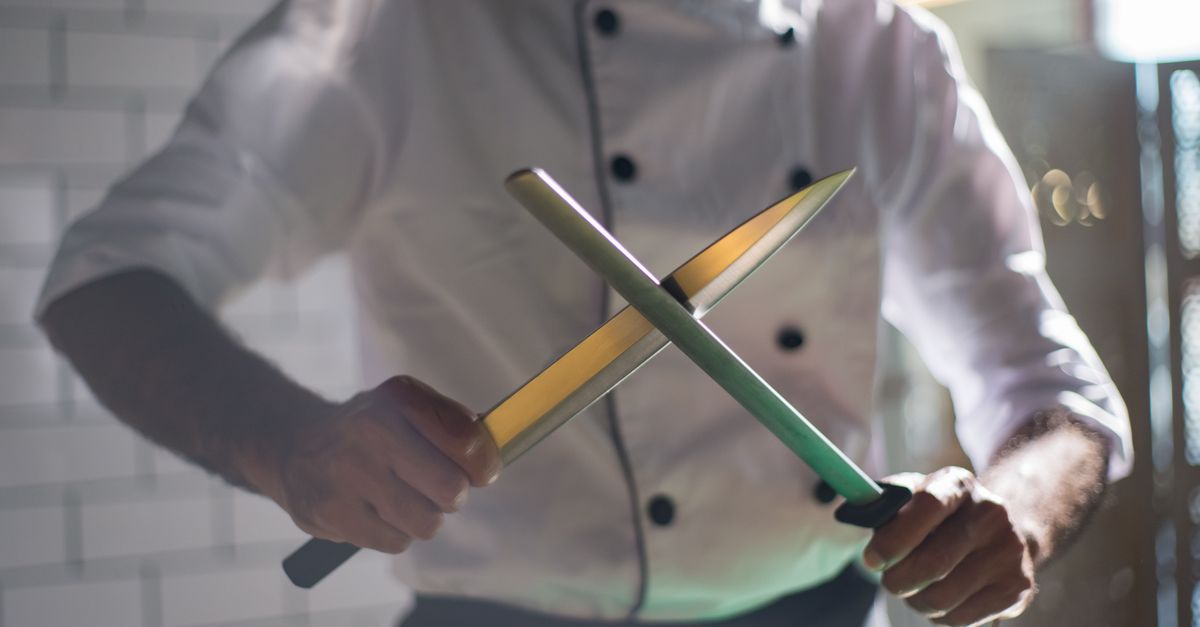 Cozinheiro afiando uma faca com uma chaira