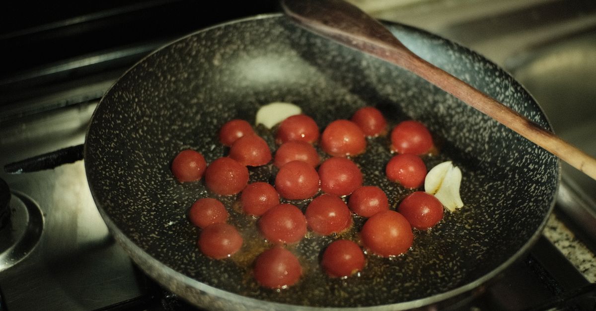 Tomates-cereja e alho refogando em uma frigideira