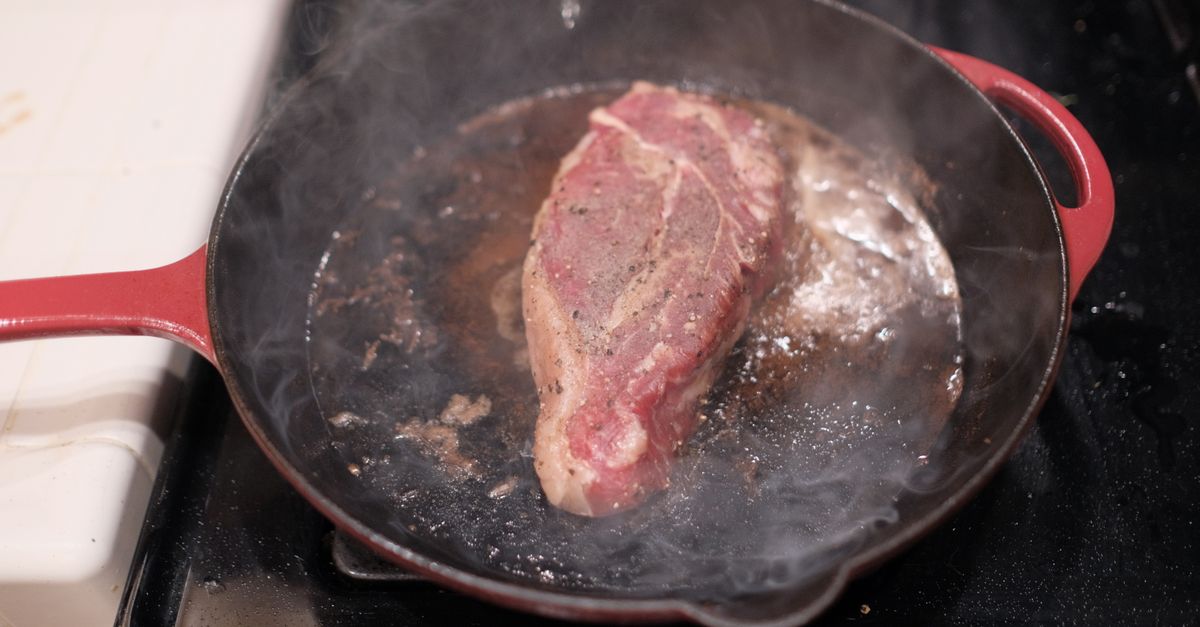 Bife dourando em uma frigideira de ferro fundido
