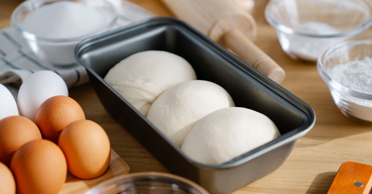 Massa crua em uma forma de pão, com ovos e ingredientes ao redor