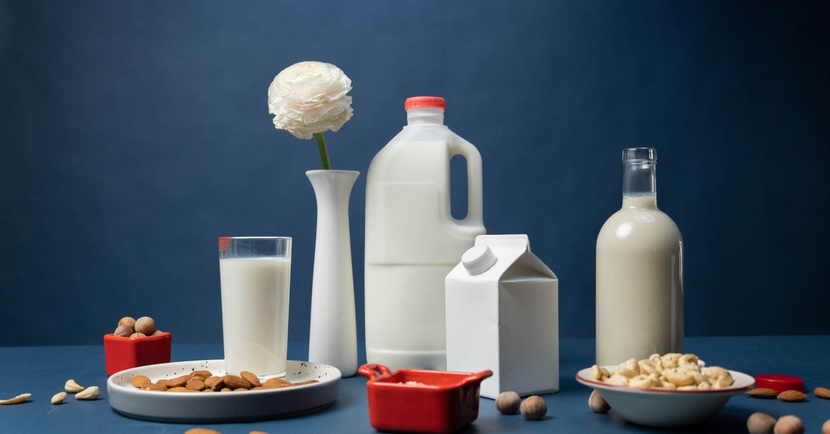 Garrafas e caixas de leite e bebidas vegetais sobre fundo azul